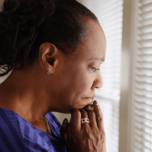 A middle-aged woman thinking deeply with her hands under her chin